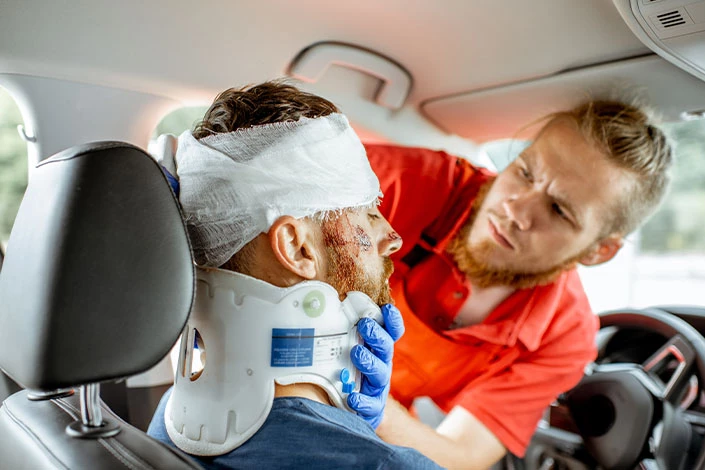 Medic applying head bandages to a driver with a closed head injury after a car accident